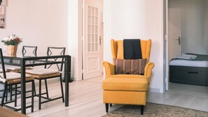 A room with a dining table, chairs, a yellow armchair, a bed, and a door. - 03 Nice Flat by Travessa do Pasteleiro (Lisbon)