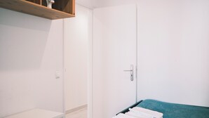A bedroom with a bed, a wardrobe, and a shelf with items. - 03 Nice Flat by Travessa do Pasteleiro (Lisbon)