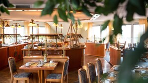 Un restaurante espacioso con varias áreas de comedor, un bar central y una cocina visible al fondo.