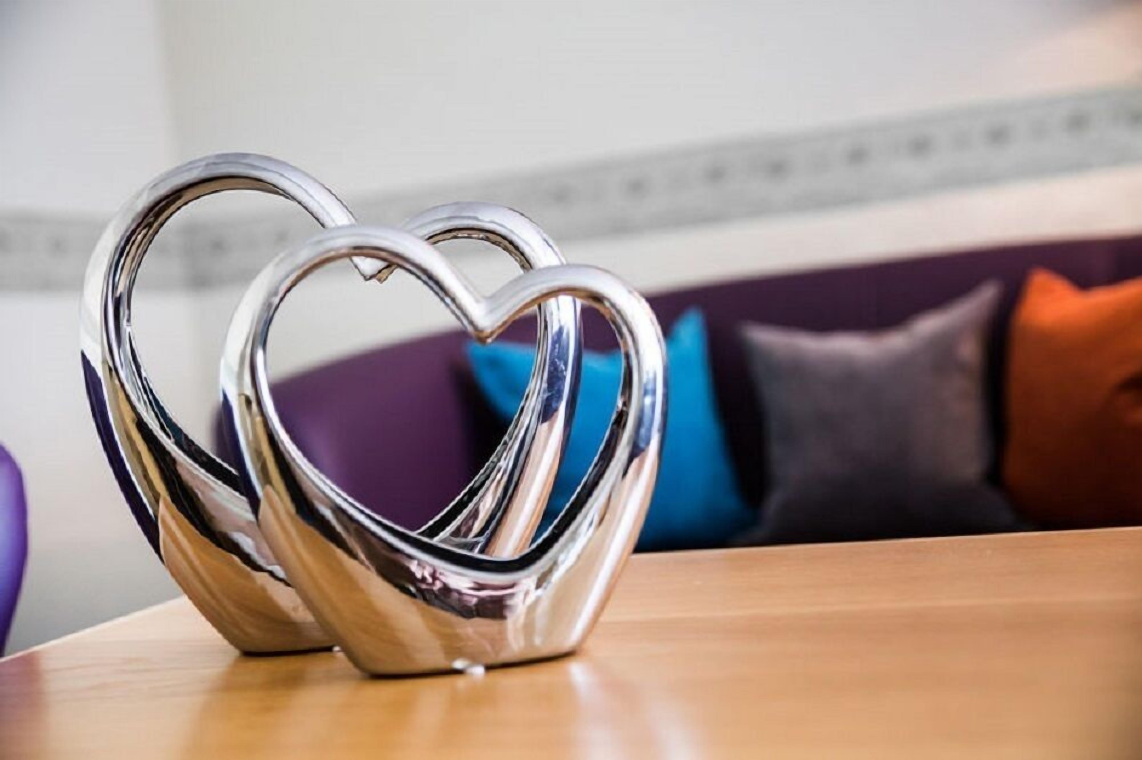 A heart-shaped metallic sculpture on a wooden table.