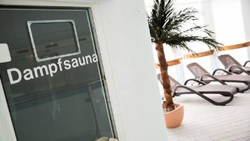 Relax in the Dampfsauana, featuring a glass door and comfortable lounge chairs.