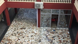 A tiled floor with a mosaic pattern, a red-framed entrance, and a glass door with a red chair inside.