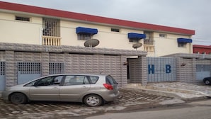 A building with a patterned facade, satellite dishes, and a car parked in front.