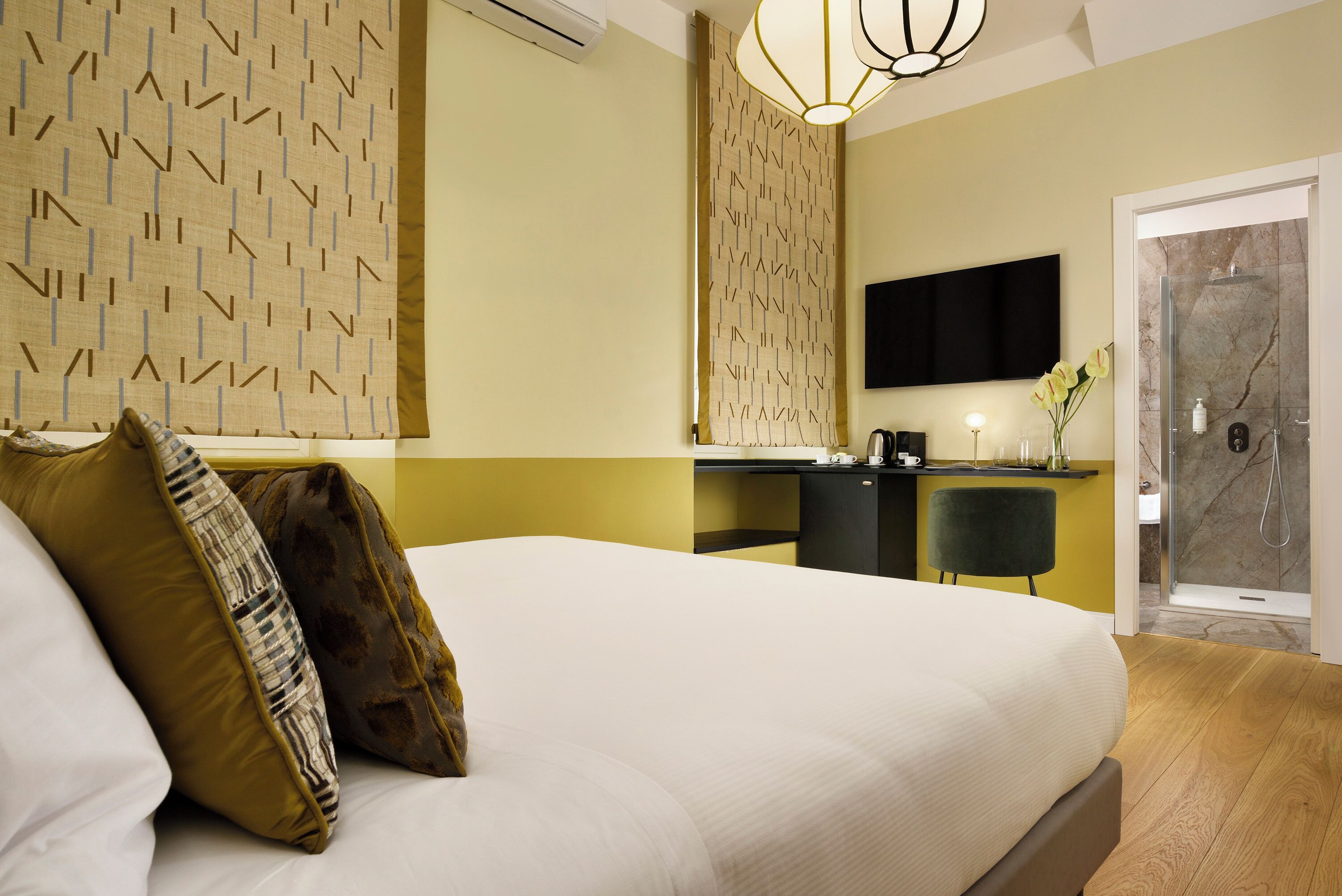 Een hotelkamer met een groot bed, een bureau, een stoel, een televisie en een douche.