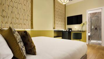 Een hotelkamer met een groot bed, een bureau, een stoel, een televisie en een douche.