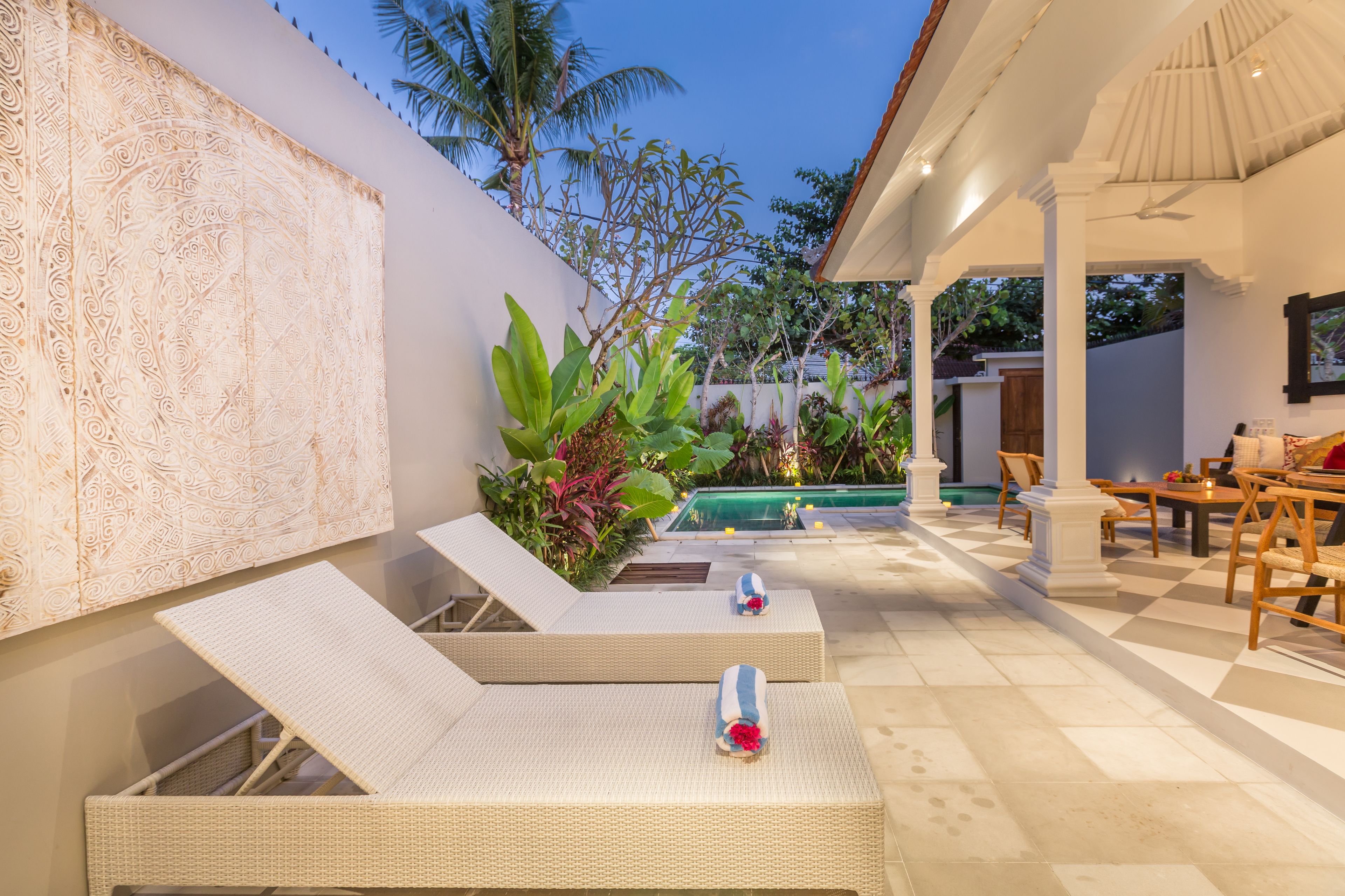 A poolside area with lounge chairs, a pool, and a dining area.