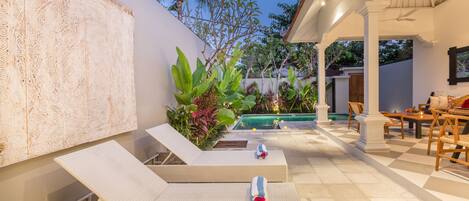 A poolside area with lounge chairs, a pool, and a dining area.