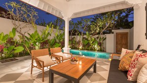 An outdoor patio with a pool, seating area, and lush greenery. - Villa CJ (Seminyak)