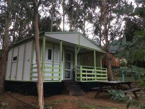 A small, single-story cabin with a green porch and a small deck. - Camping du Soleil (Appietto)