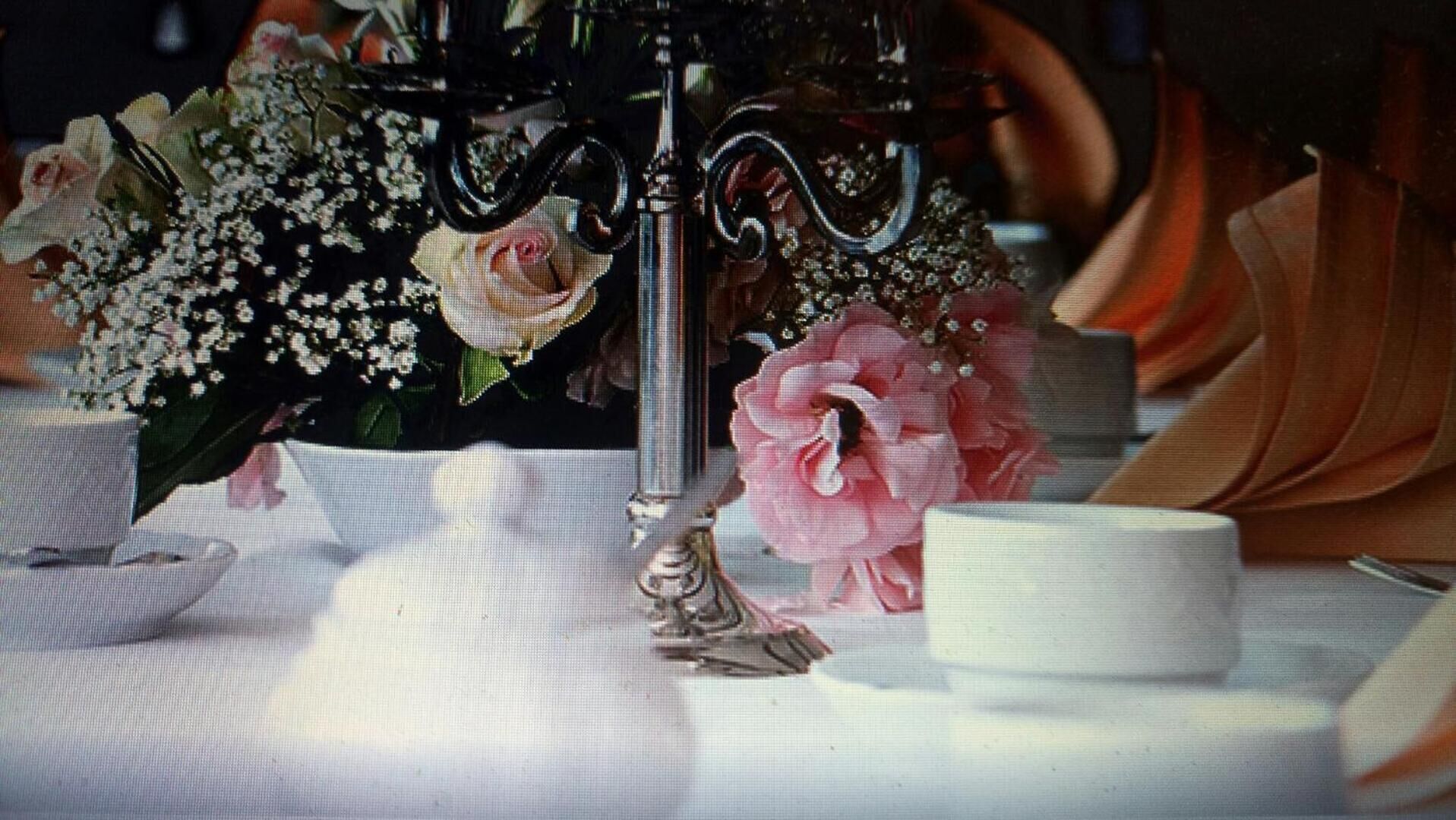 A table with a floral arrangement, a candle holder, and a white bowl.