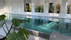 Une piscine intérieure moderne, avec des murs en marbre et des plantes en pot.