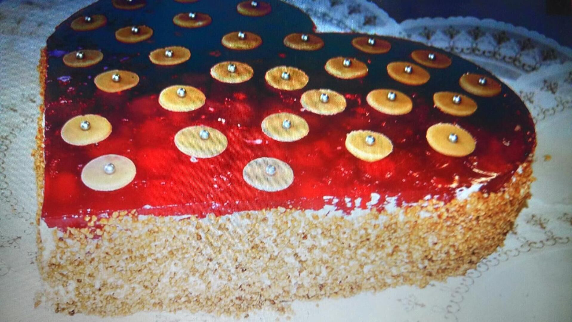 A slice of cake with a red glaze and golden buttons on top.
