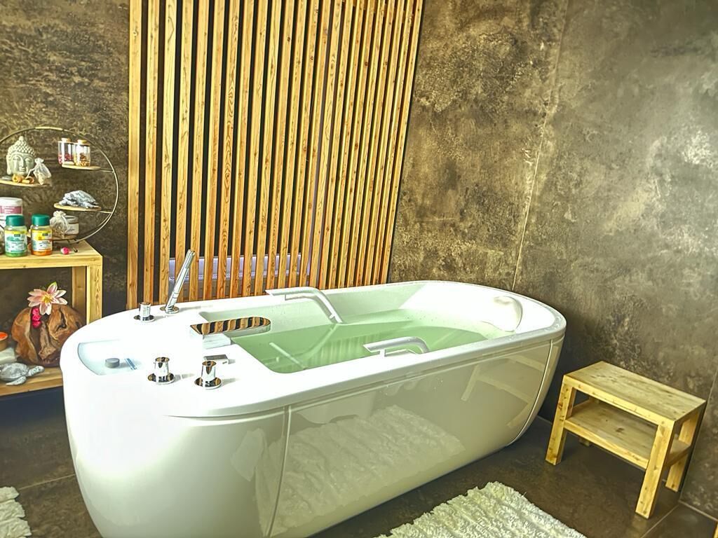 Un baño moderno con una bañera independiente, un taburete de madera pequeño y un estante con artículos de aseo.