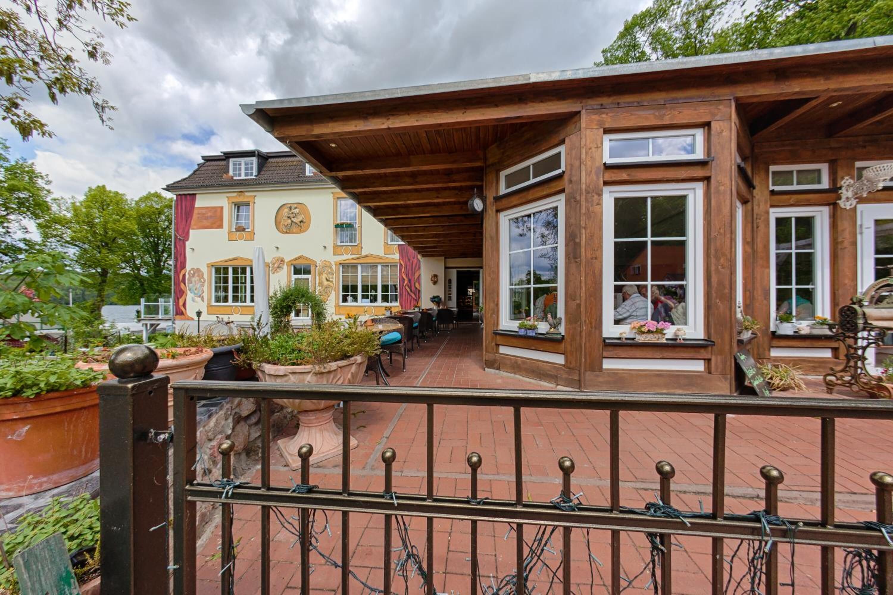 Un bâtiment de style européen traditionnel, doté d’une façade en bois, de grandes fenêtres et d’un chemin en briques menant à l’entrée.
