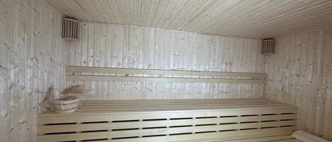 A sauna with wooden benches and slatted floors, and ventilation vents on the walls.
