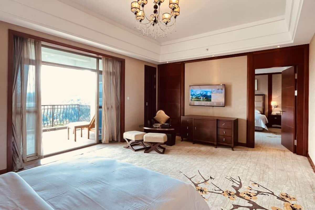 Una habitación de hotel con una cama grande, un escritorio, un televisor y un balcón con una silla.