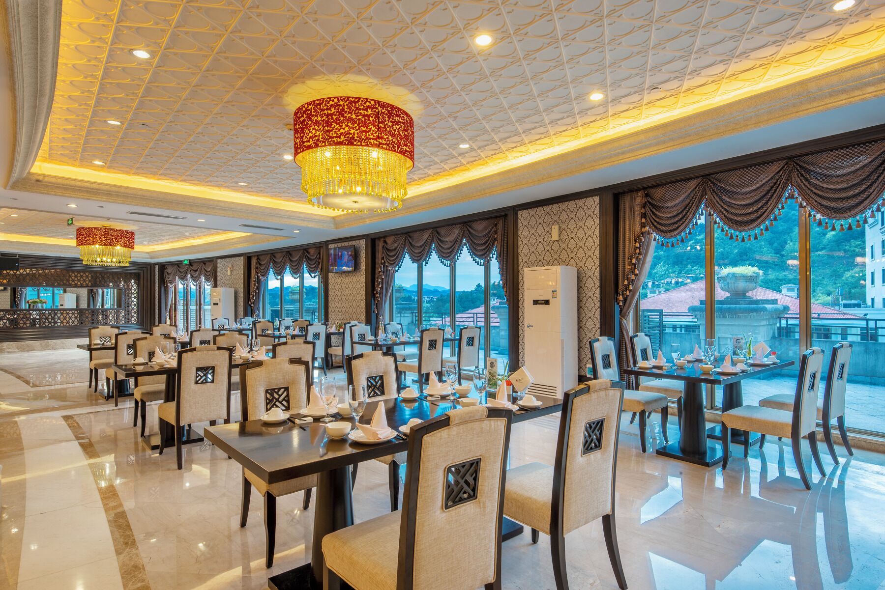 Ein geräumiges Restaurant mit hohen Decken, Kronleuchtern und großen Fenstern mit Blick ins Freie.