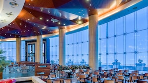 A spacious restaurant with high ceilings, large windows, and a central fountain.