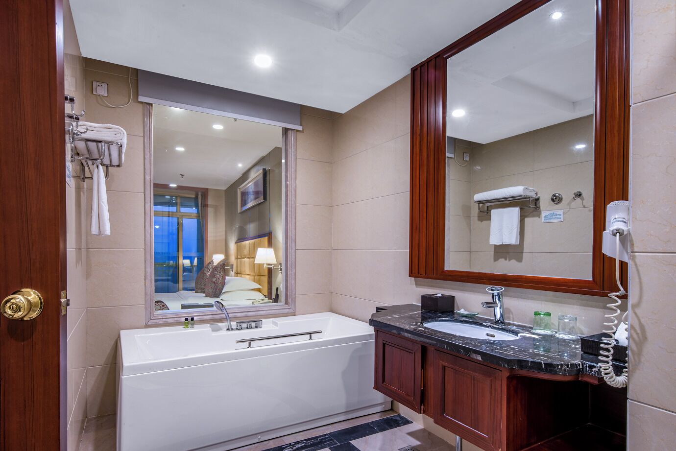 A modern bathroom with a bathtub, a vanity with a mirror, and a hairdryer.