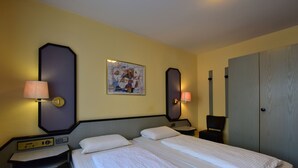 Habitación de hotel con cama doble, dos mesitas de noche, un escritorio con lámpara, un cuadro en la pared y un armario.