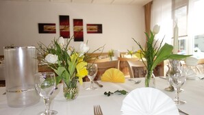 Mesa de comedor puesta con mantel blanco, cristalería y centros de mesa florales.