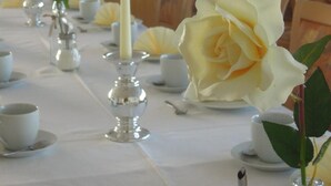 Una mesa de comedor vestida con manteles blancos, velas y centros de mesa florales.