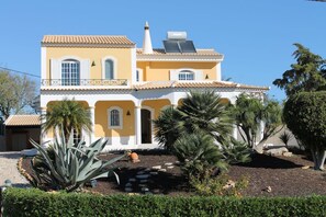 Un edificio di due piani con facciata gialla, cornici bianche e un balcone.