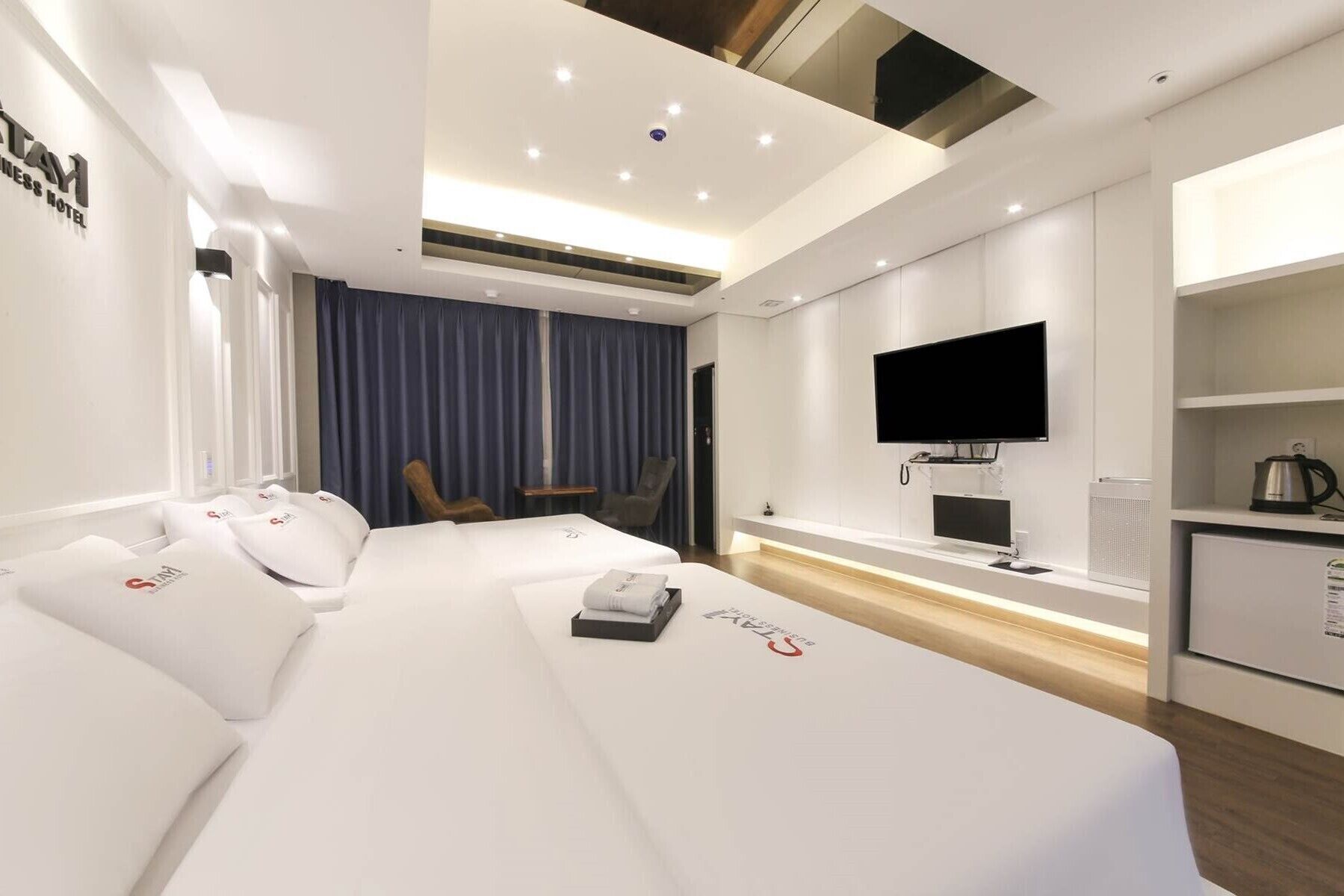 Una habitación de hotel con una cama grande, televisión, escritorio y kitchenette.