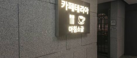 A sign with Korean text on a stone wall, indicating a coffee shop.