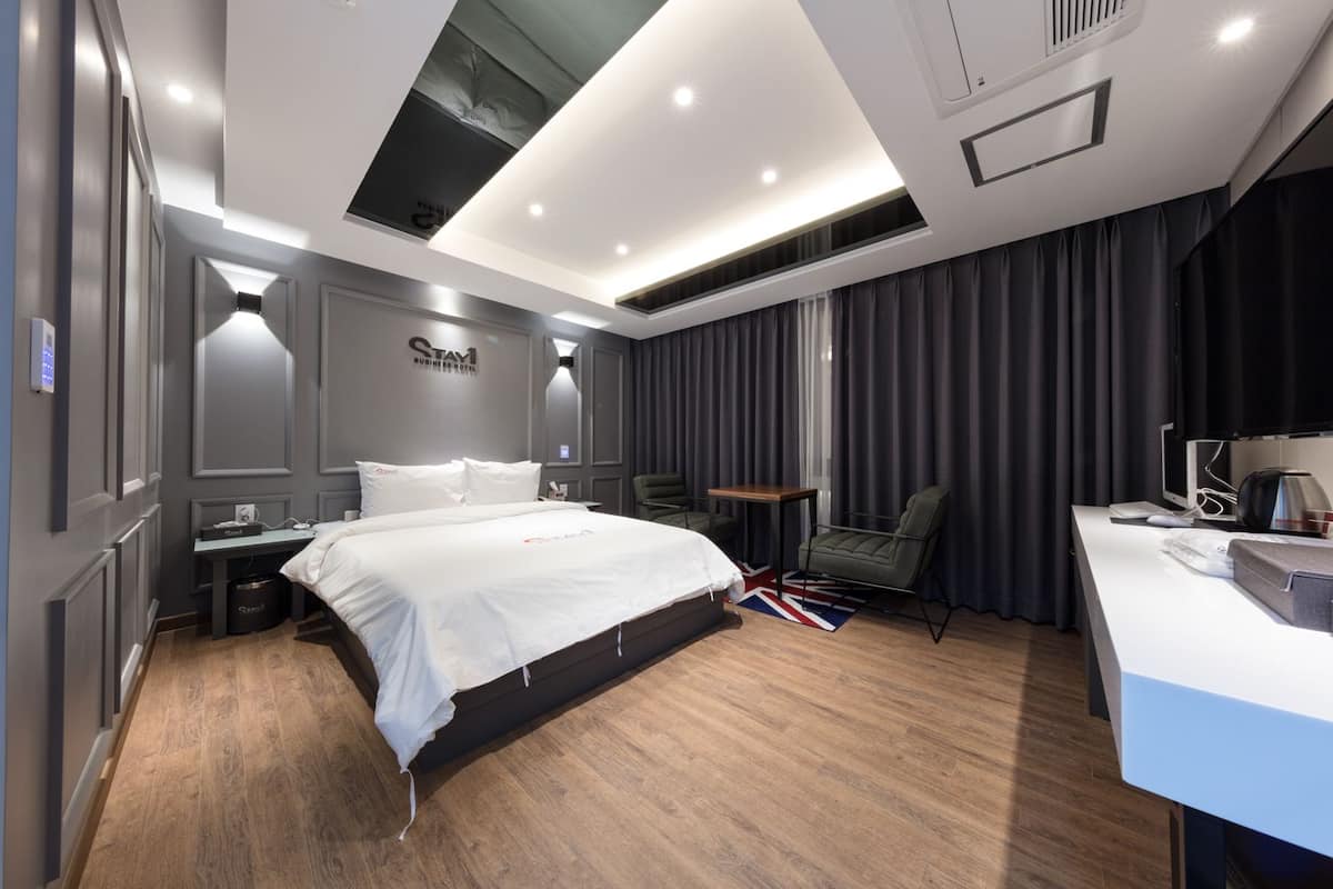 A modern hotel room with a large bed, a desk, and a chair.