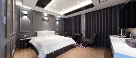 A modern hotel room with a large bed, a desk, and a chair.