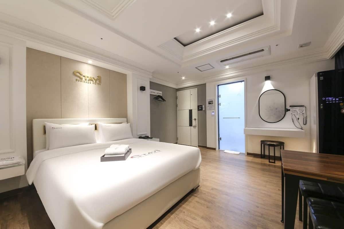 A hotel room with a large bed, a desk, and a mirror.