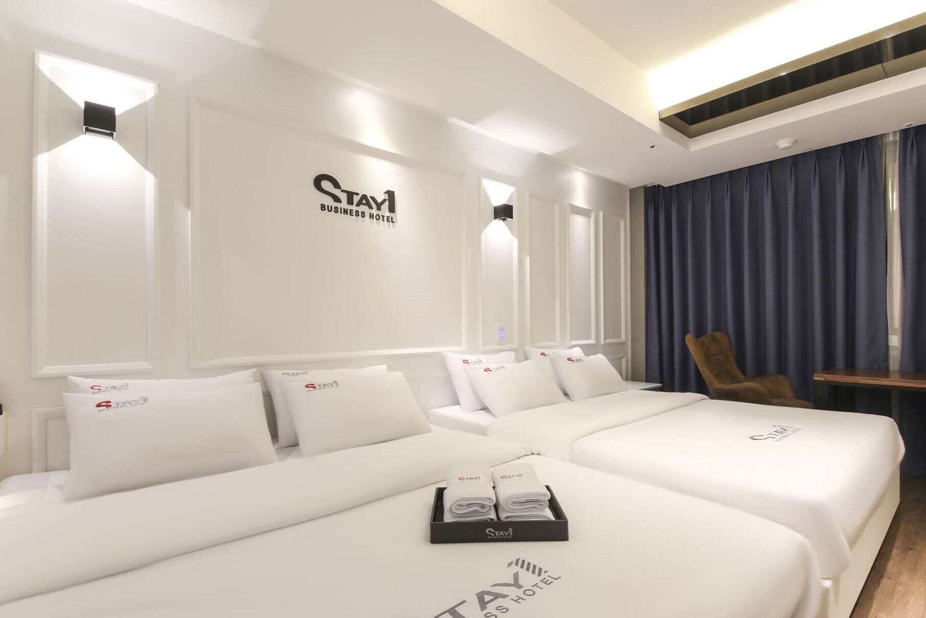 Una habitación de hotel con una cama grande, dos camas más pequeñas, una silla y un escritorio.