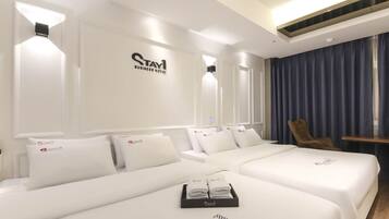 Una habitación de hotel con una cama grande, dos camas más pequeñas, una silla y un escritorio.