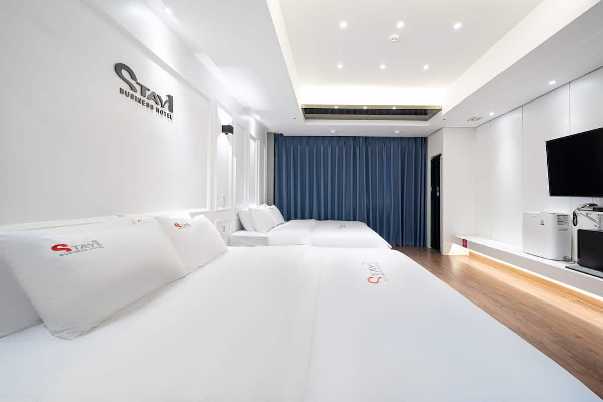 A modern hotel room with a large bed, a flat-screen TV, and a built-in air conditioning unit.