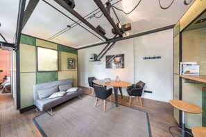 A modern interior with a sofa, round table, and chairs, a painting on the wall, and a wooden cabinet with a sign.