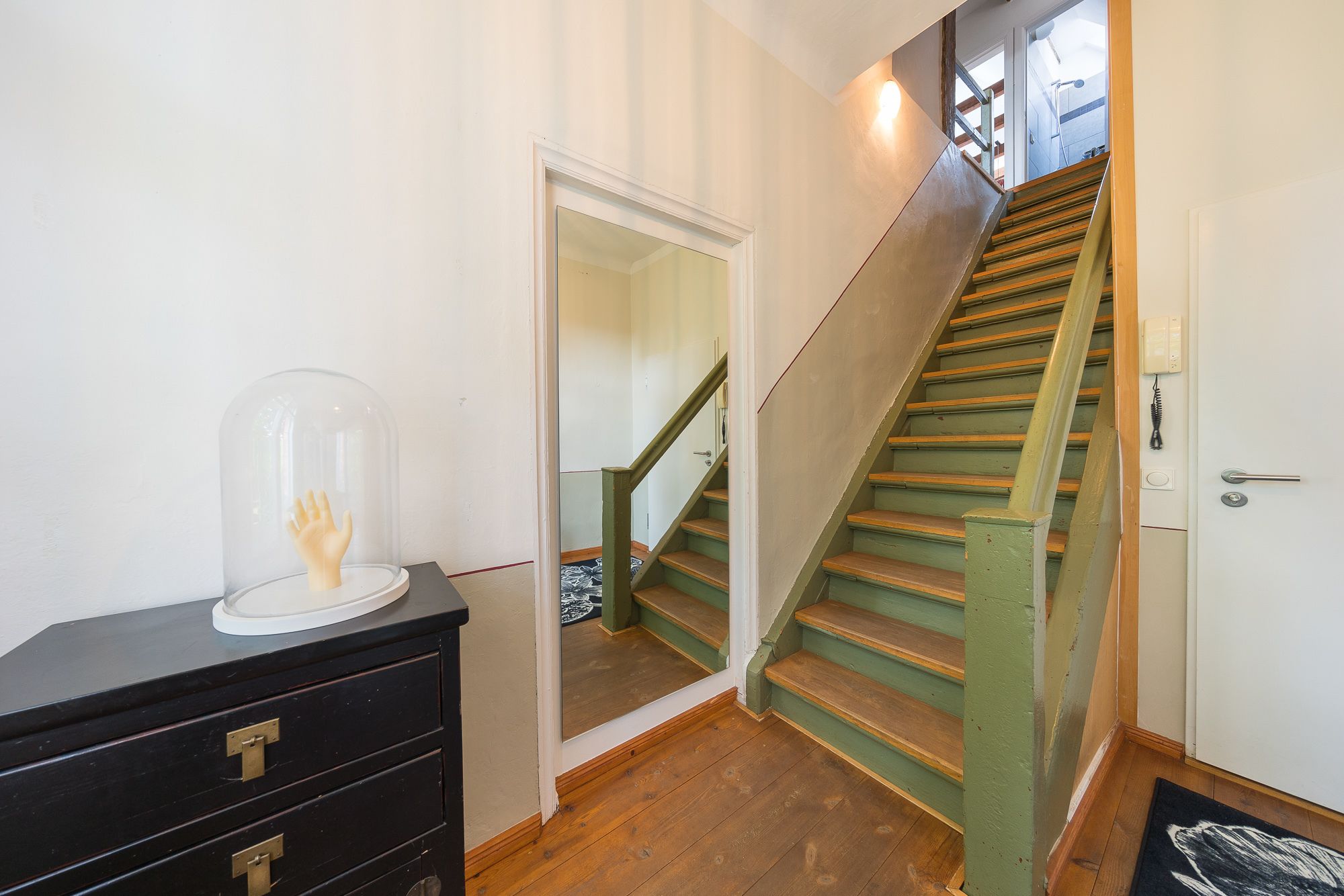 Una escalera de madera con barandilla verde que lleva al segundo piso.