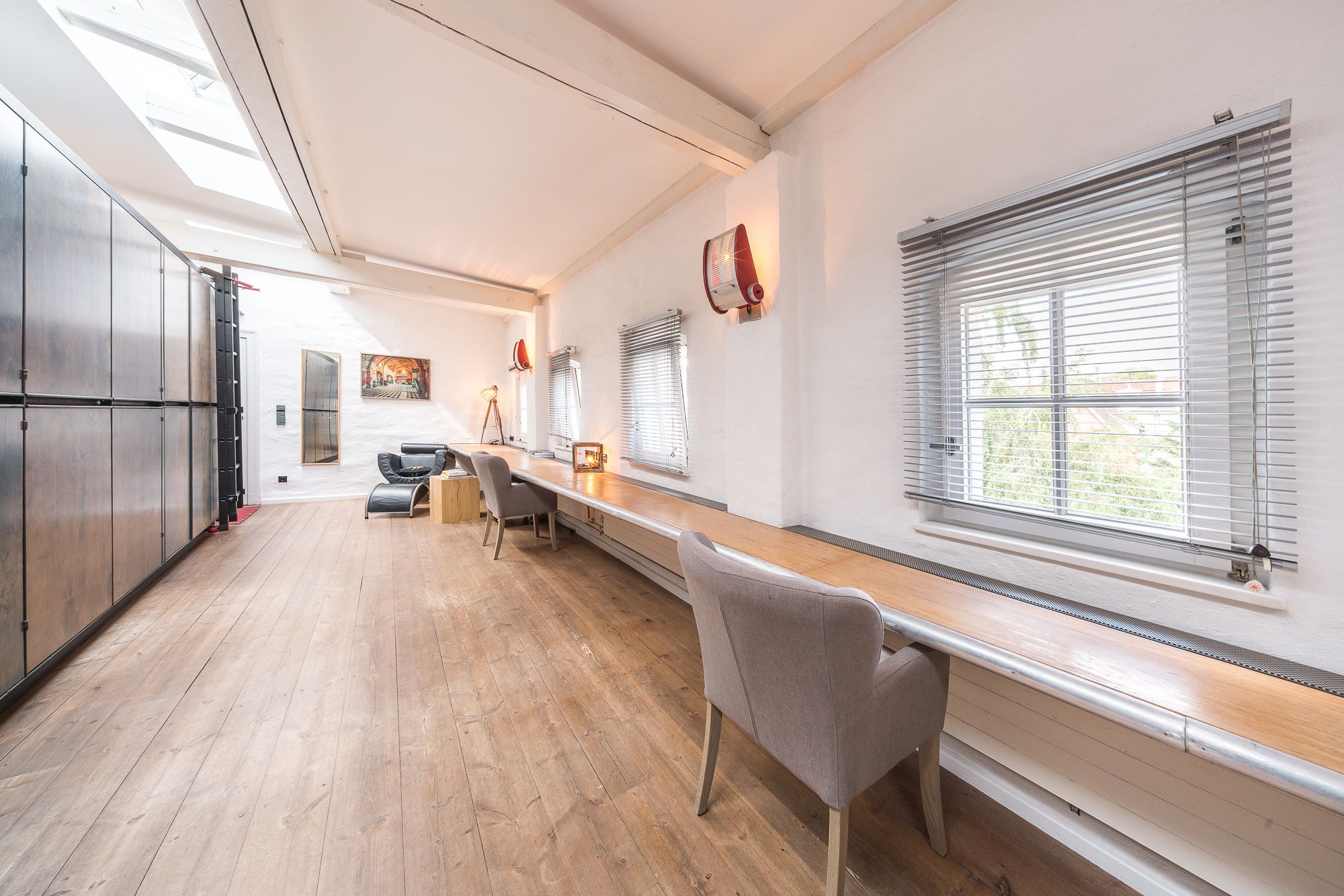 A spacious kitchen with a long counter, wooden cabinets, and a view of the outdoors through large windows.