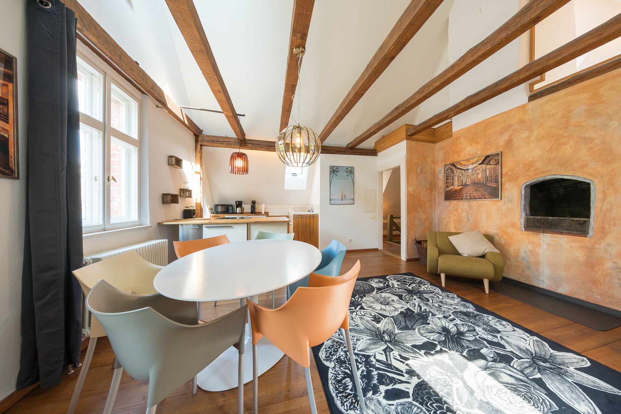 A spacious living area with a dining table, chairs, a sofa, and a fireplace.