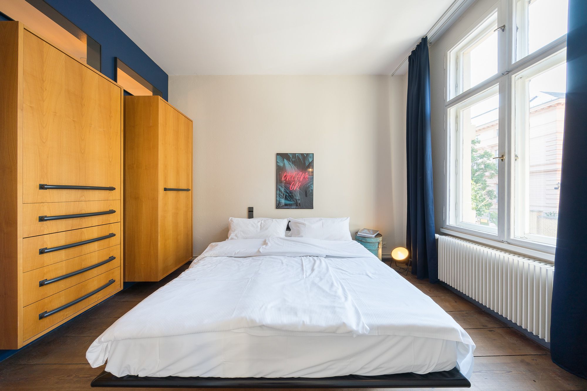 Une chambre à coucher avec un lit, une armoire en bois et une fenêtre avec des rideaux.