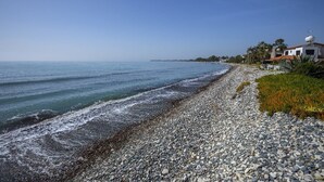 A pebble beach with a white building and a satellite dish on the roof. - Meneou Beachfront Villa 5 (Meneou)