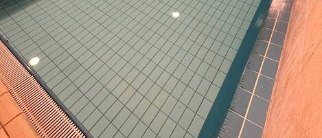 Une piscine dotée d’un sol carrelé et entourée d’un muret.