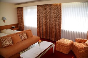 A hotel room with a bed, a sofa, a coffee table, and a chair. - Hotel Exquisit (Minden)