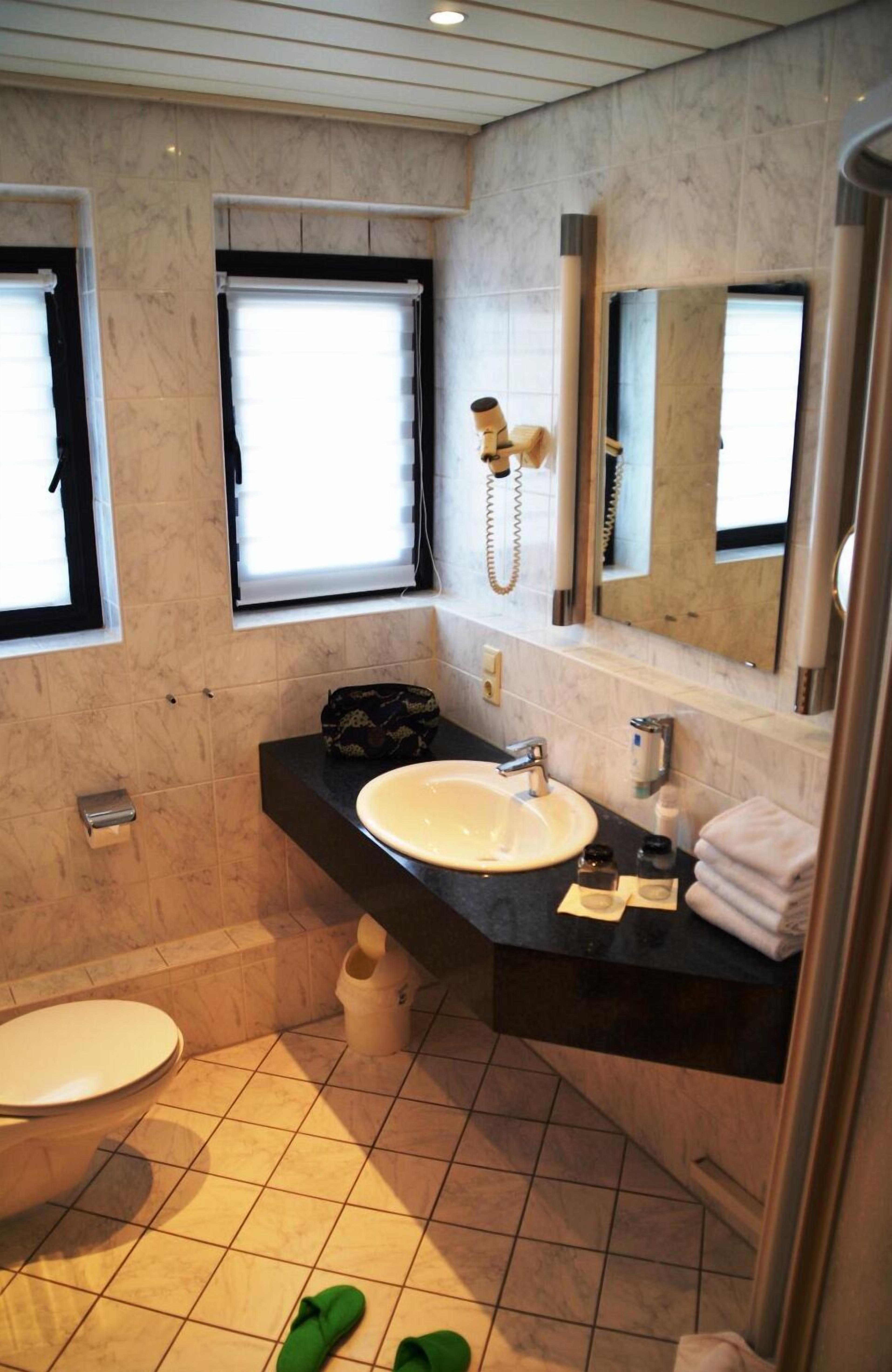 A bathroom with a toilet, sink, and mirror.