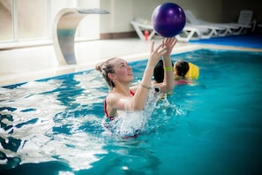 A person in a swimming pool holding a ball.