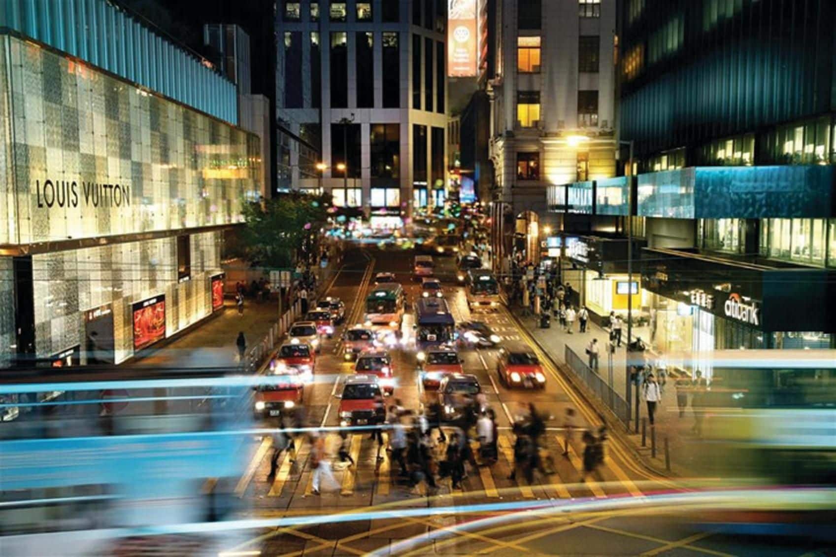 Rua movimentada na cidade, com uma loja Louis Vuitton à esquerda.