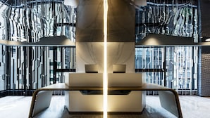 Un interior moderno con una zona de estar central, paredes reflectantes y un techo con diseño.