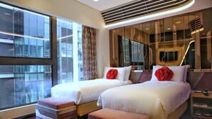 Habitación de hotel moderna con dos camas, un ventanal grande y vista a la ciudad.