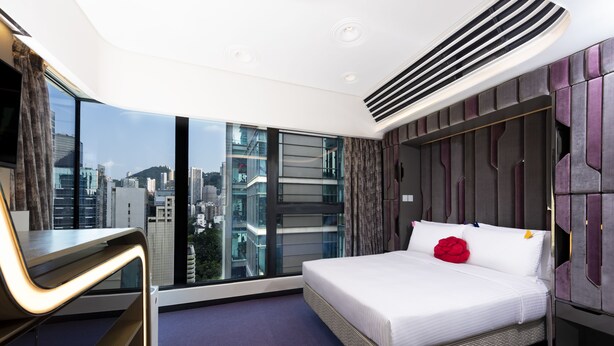 Una habitación de hotel moderna con una cama grande, un escritorio y vistas a la ciudad.