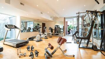 Ein Fitnessstudio mit Laufband, Kraftgeräten und Kurzhanteln.
